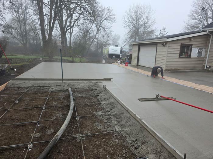 Concrete driveway pour in progress beside a residential garage