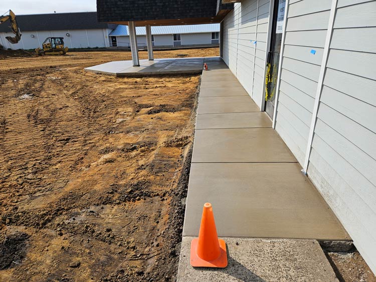 New concrete walkway and covered slab beside a building during construction