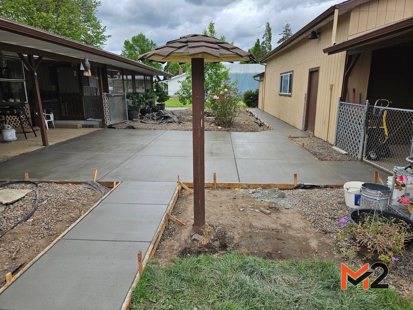 New concrete patio and connecting sidewalk installation creating a clean, functional backyard outdoor space.